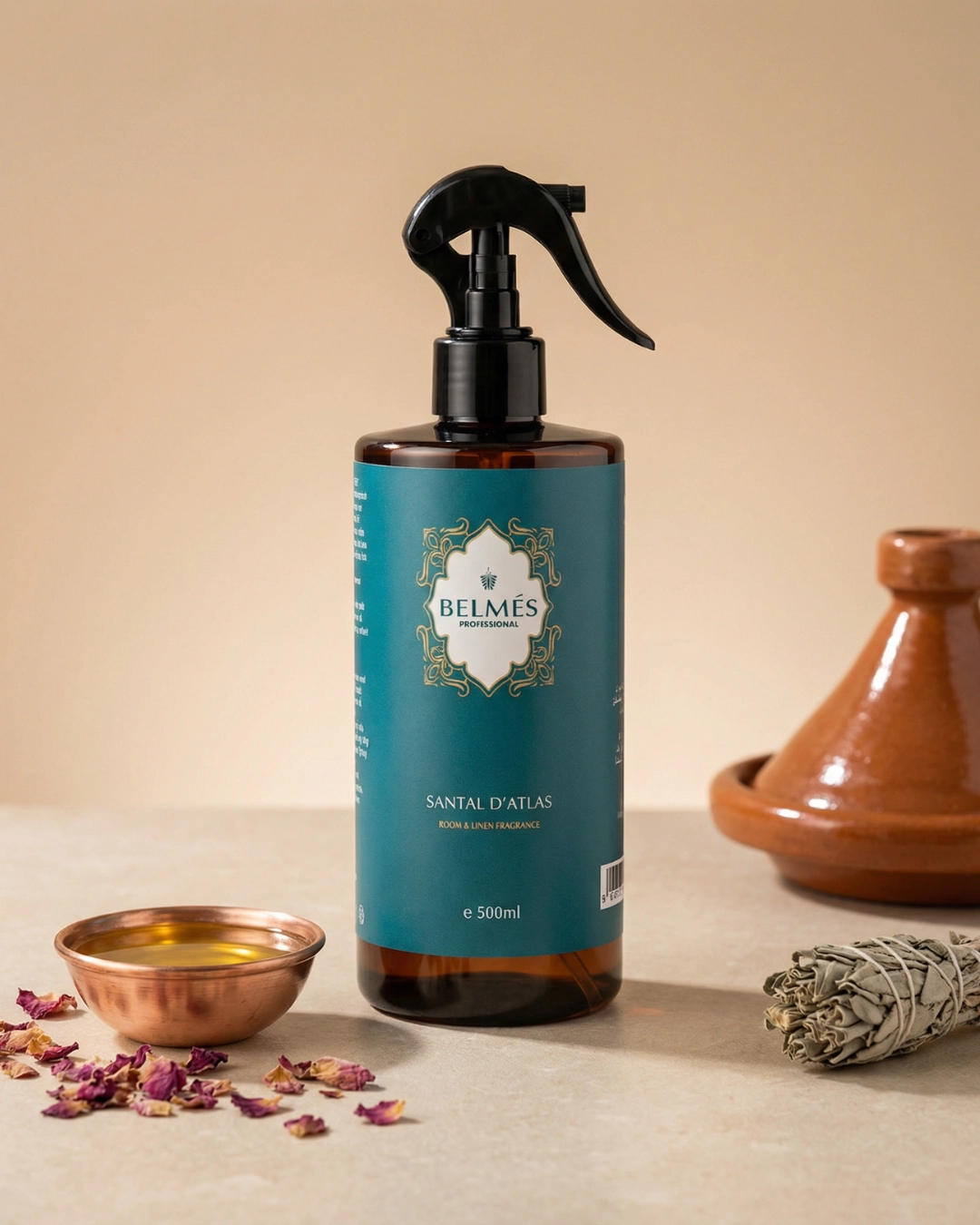Flacon spray parfum d'ambiance Santal d'Atlas Belmés Profissional 500ml – bol cuivré huile pétales de rose sauge blanche et tajine en terre cuite en arrière-plan