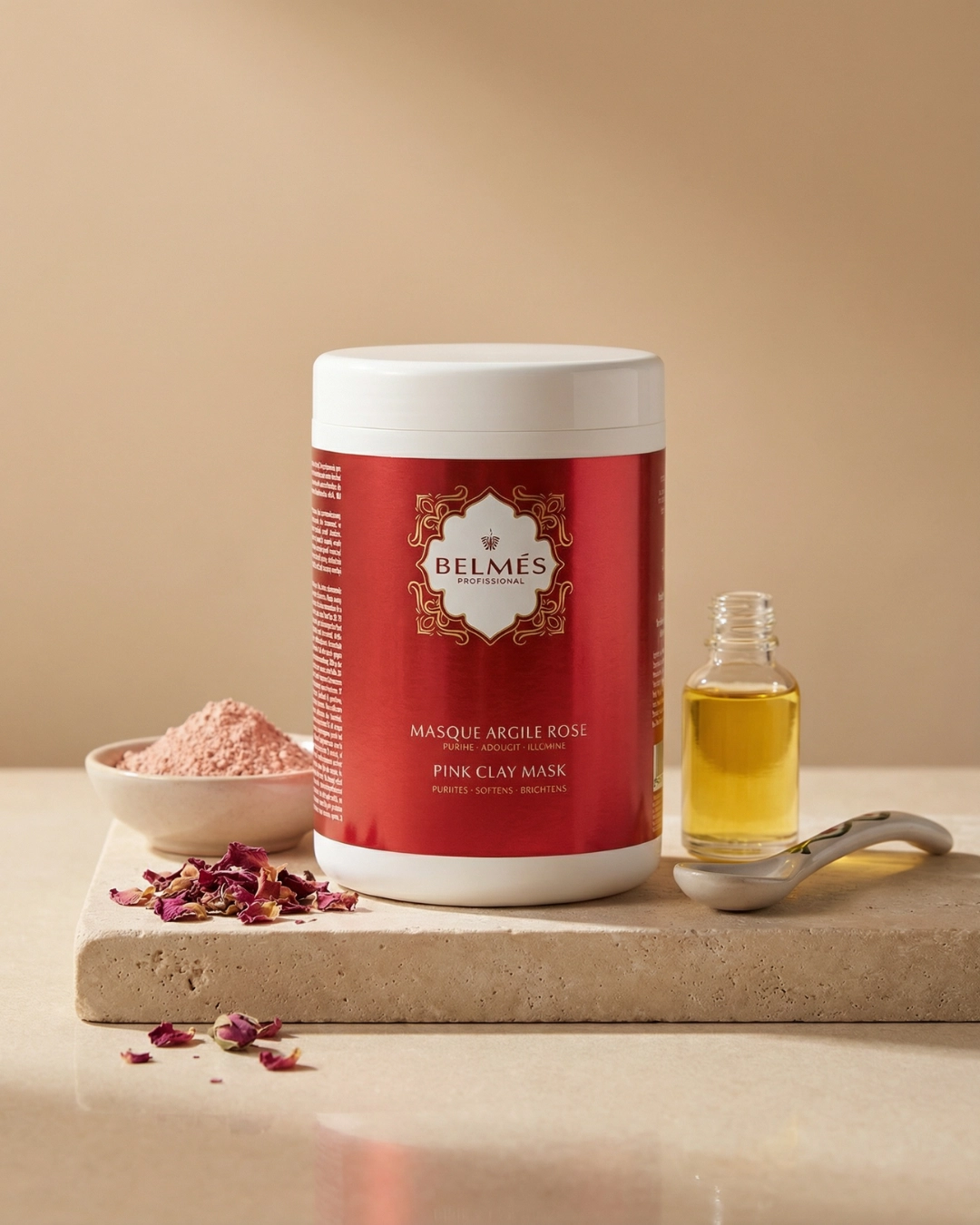 Pot masque argile rose Belmés Profissional – poudre d'argile rose pétales de rose séchés et flacon d'huile dorée en arrière-plan